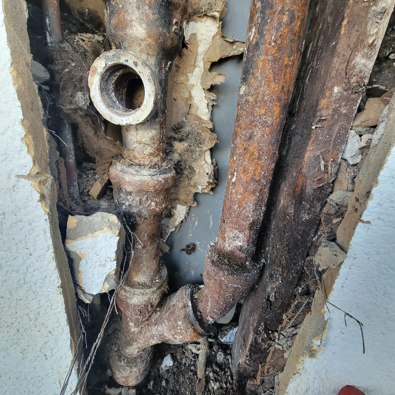 Corroded galvanized drain pipe exposed inside a wall in an East Texas home