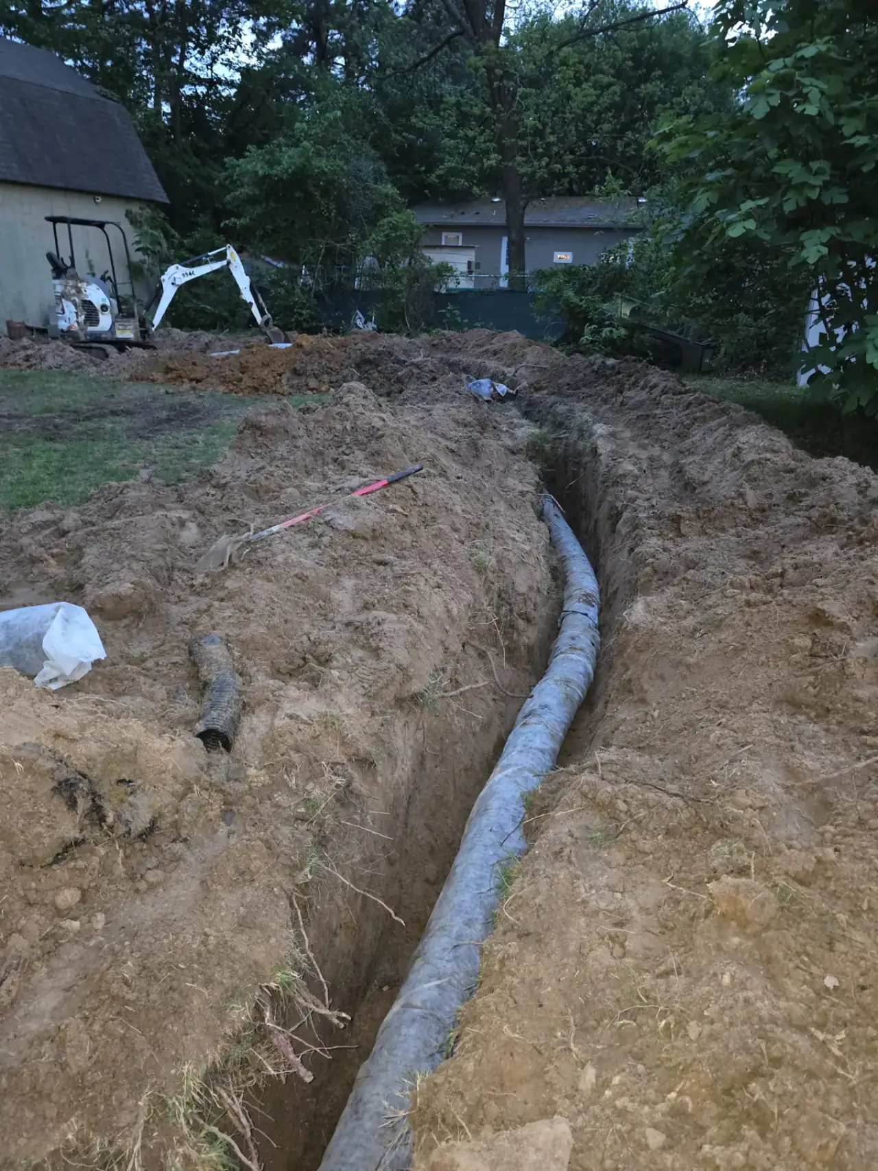 Mini excavator digging a sewer line trench at an East Texas home