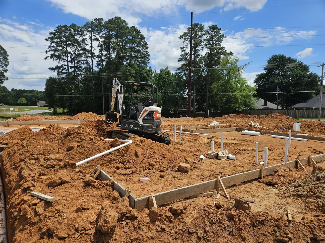 Under-slab plumbing rough-in with excavator at a new construction site in East Texas