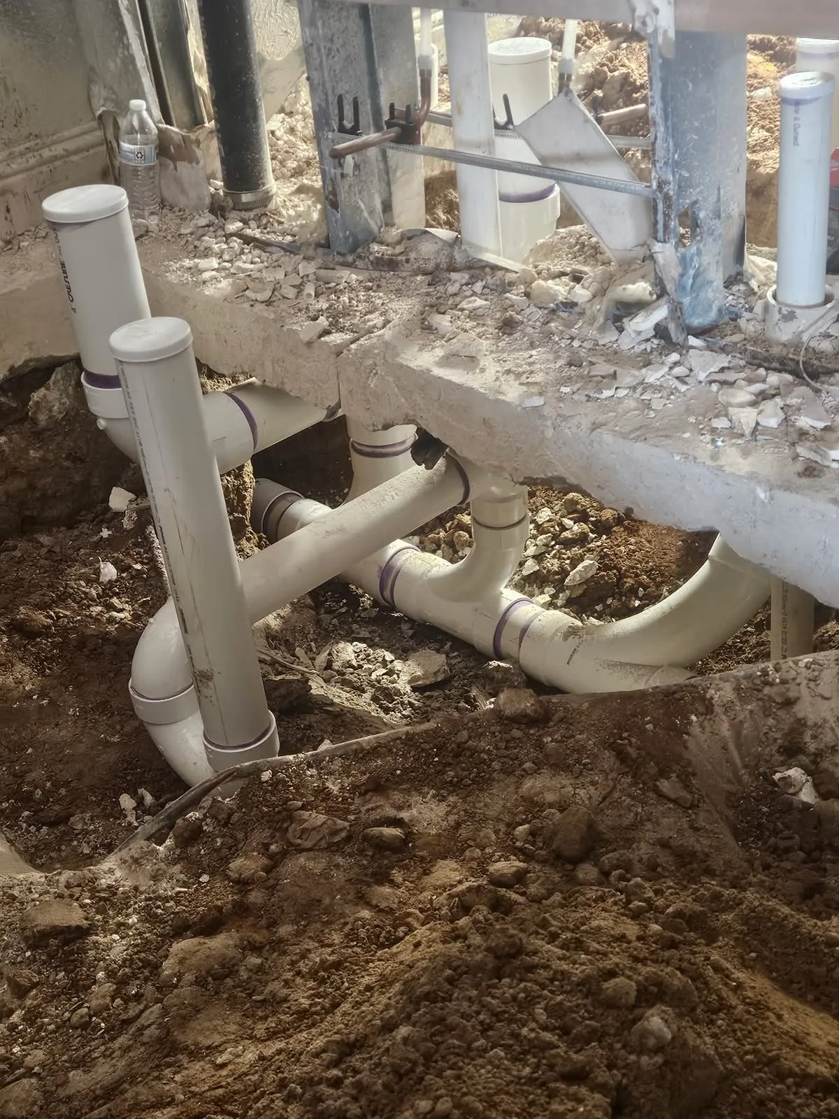 Long-radius PVC sweep elbows and capped risers under a cut slab edge