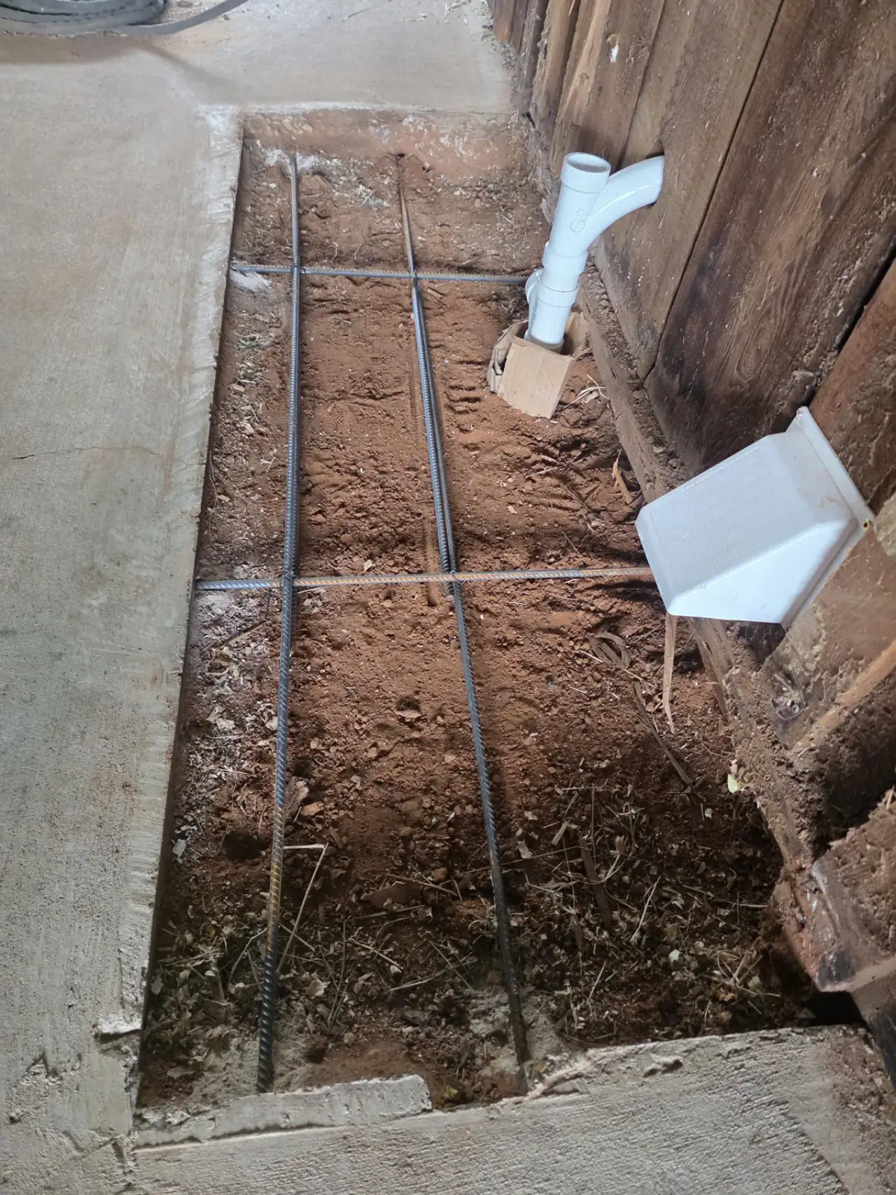 New PVC stub-ups standing in a rebar-gridded slab prep before the concrete pour in East Texas