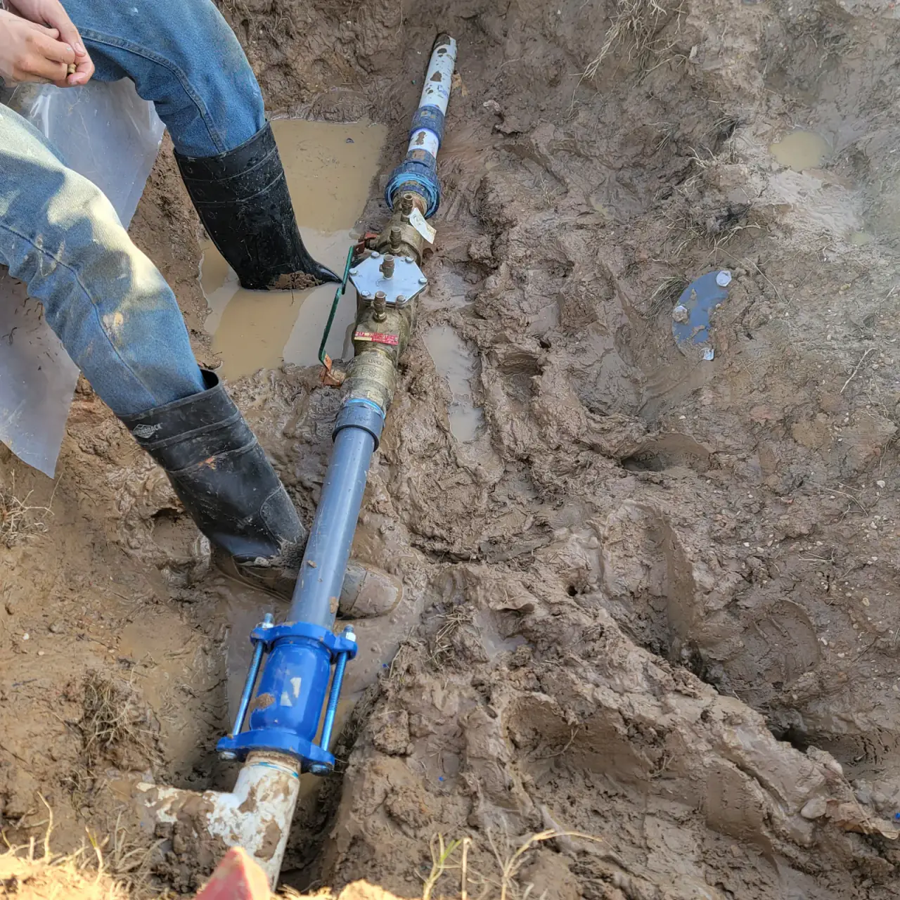 Water main connection being set in an open trench by Odyssey Plumbing Co